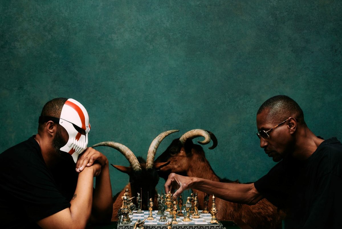 Dany Dan et Kyo Itashi sont assis, ils jouent aux échecs. Il y a deux chèvres derrière eux dans le fond.